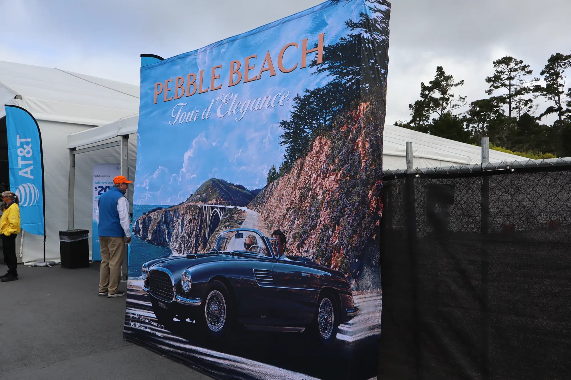 Pebble Beach Tour d’Elegance banner beside white event tents at Concours Village