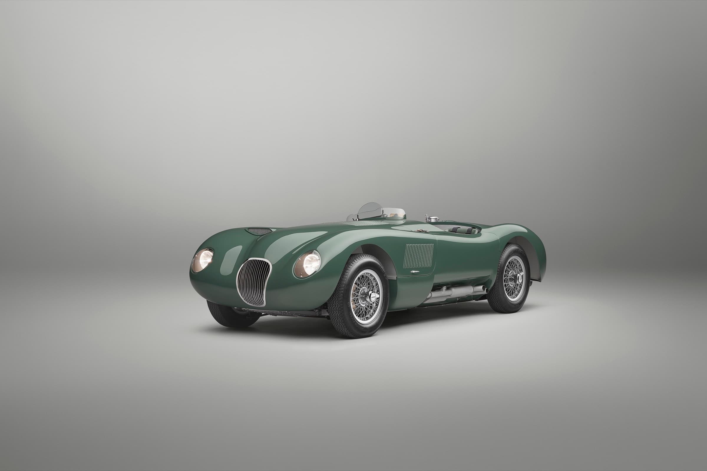 British Racing Green Jaguar C-type Continuation in three-quarter front view against a studio backdrop, headlights on