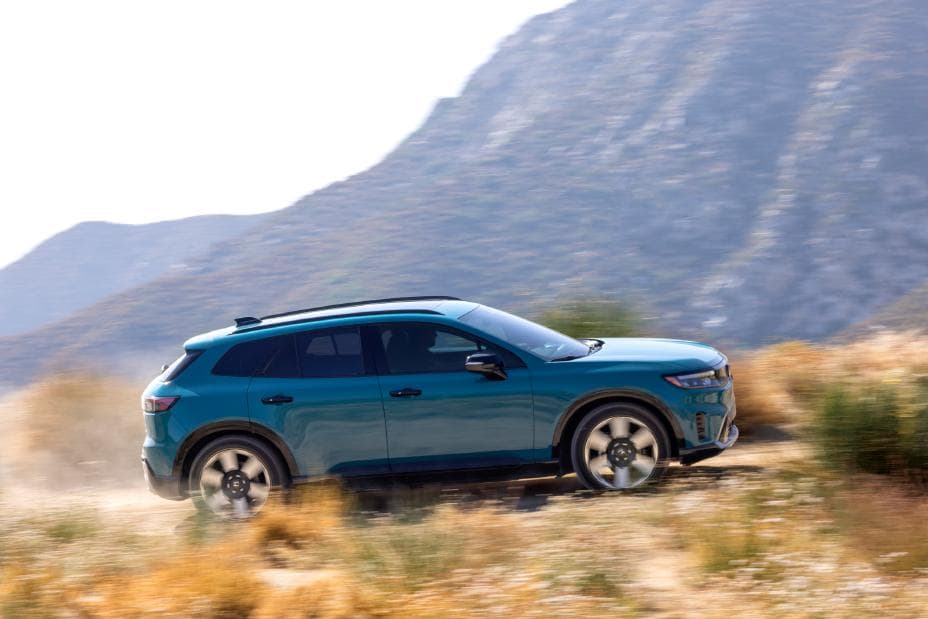 Blue 2025 Honda Prologue Elite driving past a rocky landscape