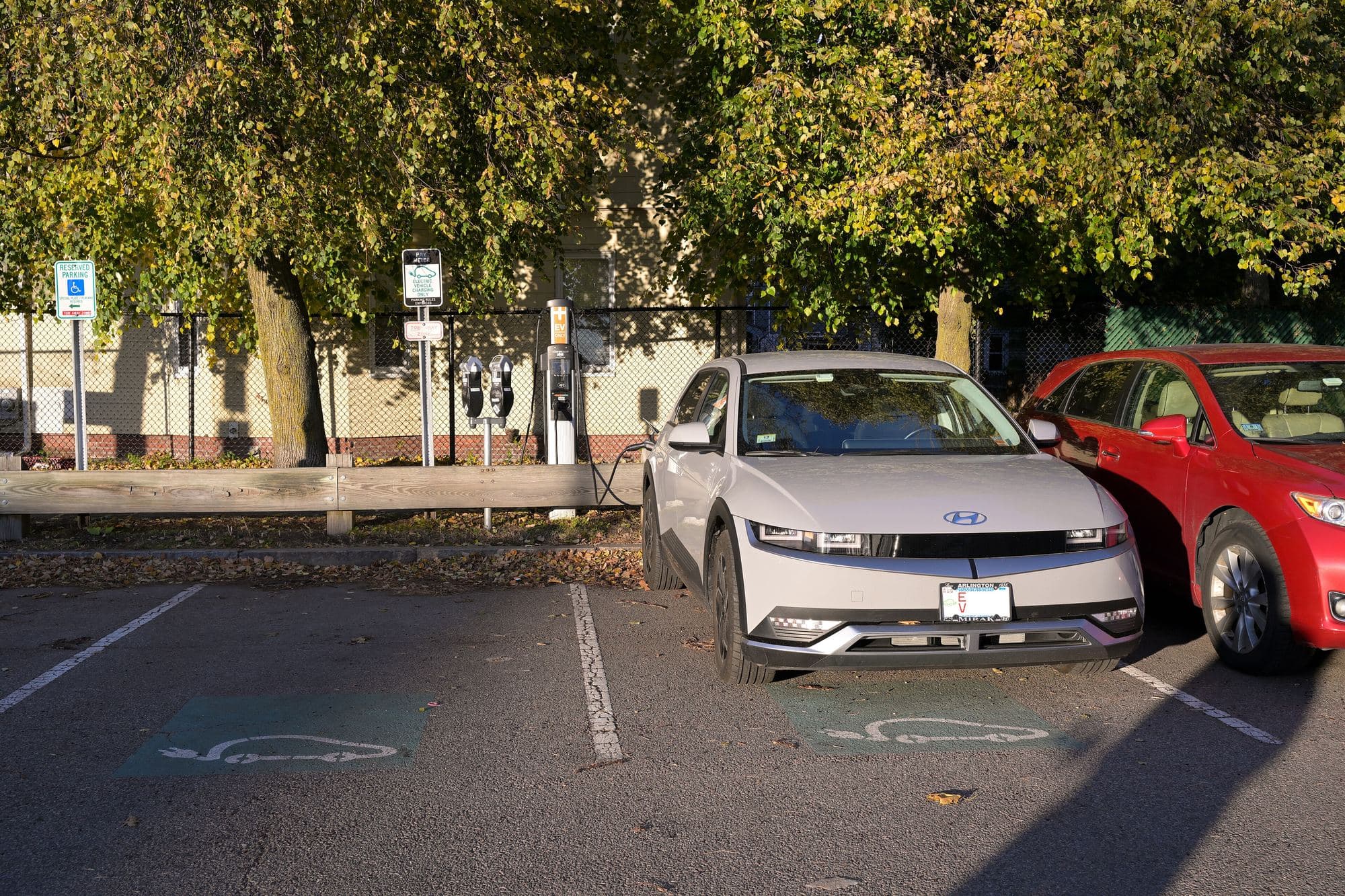 Light gray Hyundai Ioniq 5 plugged into a public ChargePoint station in a marked EV parking stall