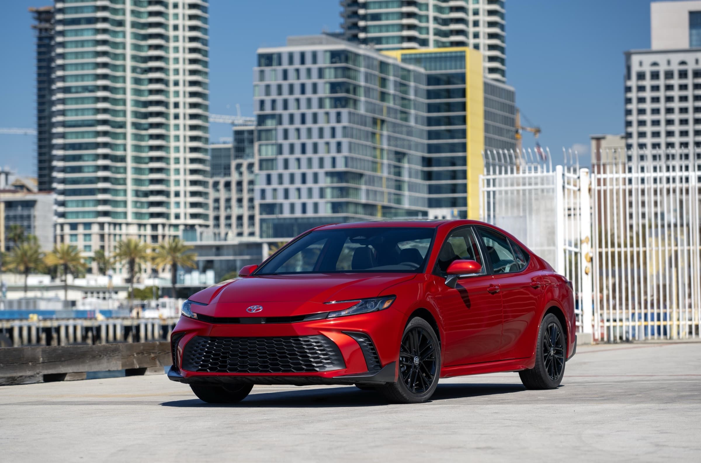 2025 Toyota Camry SE Hybrid in Supersonic Red, three-quarter front view, a trim line that uses the seven-inch instrument cluster covered by the recall
