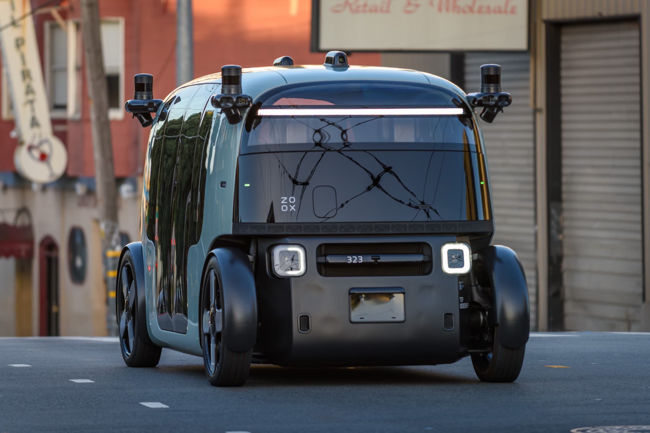Teal Zoox purpose-built robotaxi crossing a San Francisco street