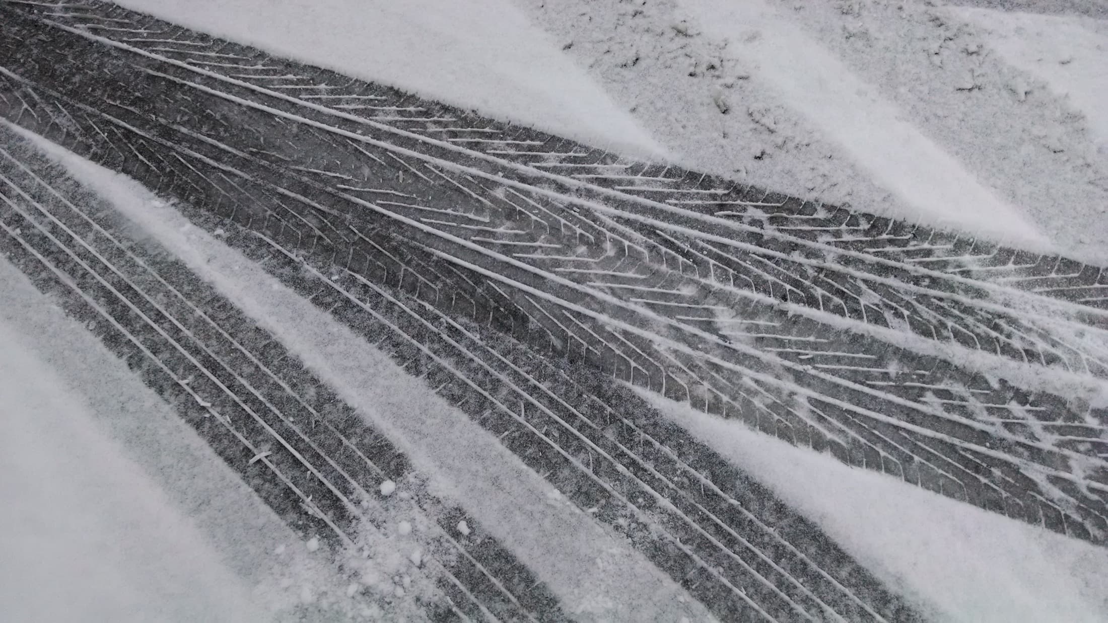 Fresh tire tracks in falling snow on a winter road